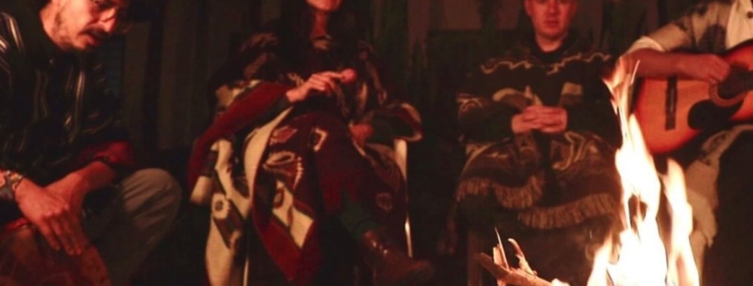 Eine Menschen sitzen während der Ayahuasca Zeremonie gemeinsam am Feuer und musizieren zusammen