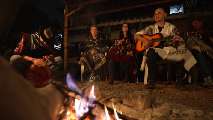 Einige Menschen sitzen während der Ayahuasca Zeremonie gemeinsam am Feuer und musizieren